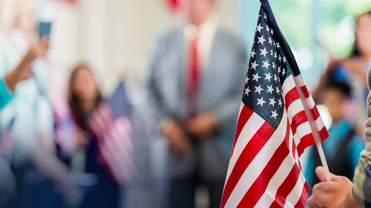 Bandera de Estados Unidos en primer plano, con personas al fondo